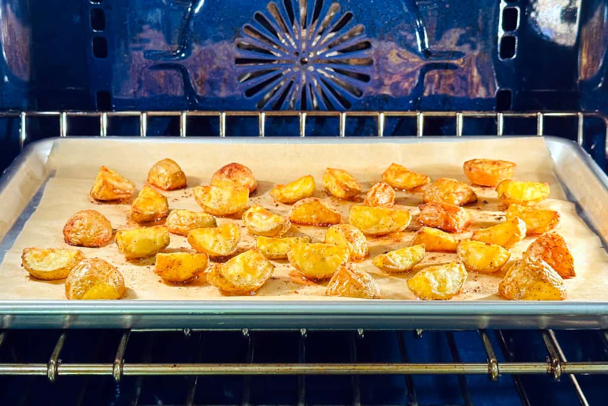 Breakfast potatoes roasting in a blue oven.