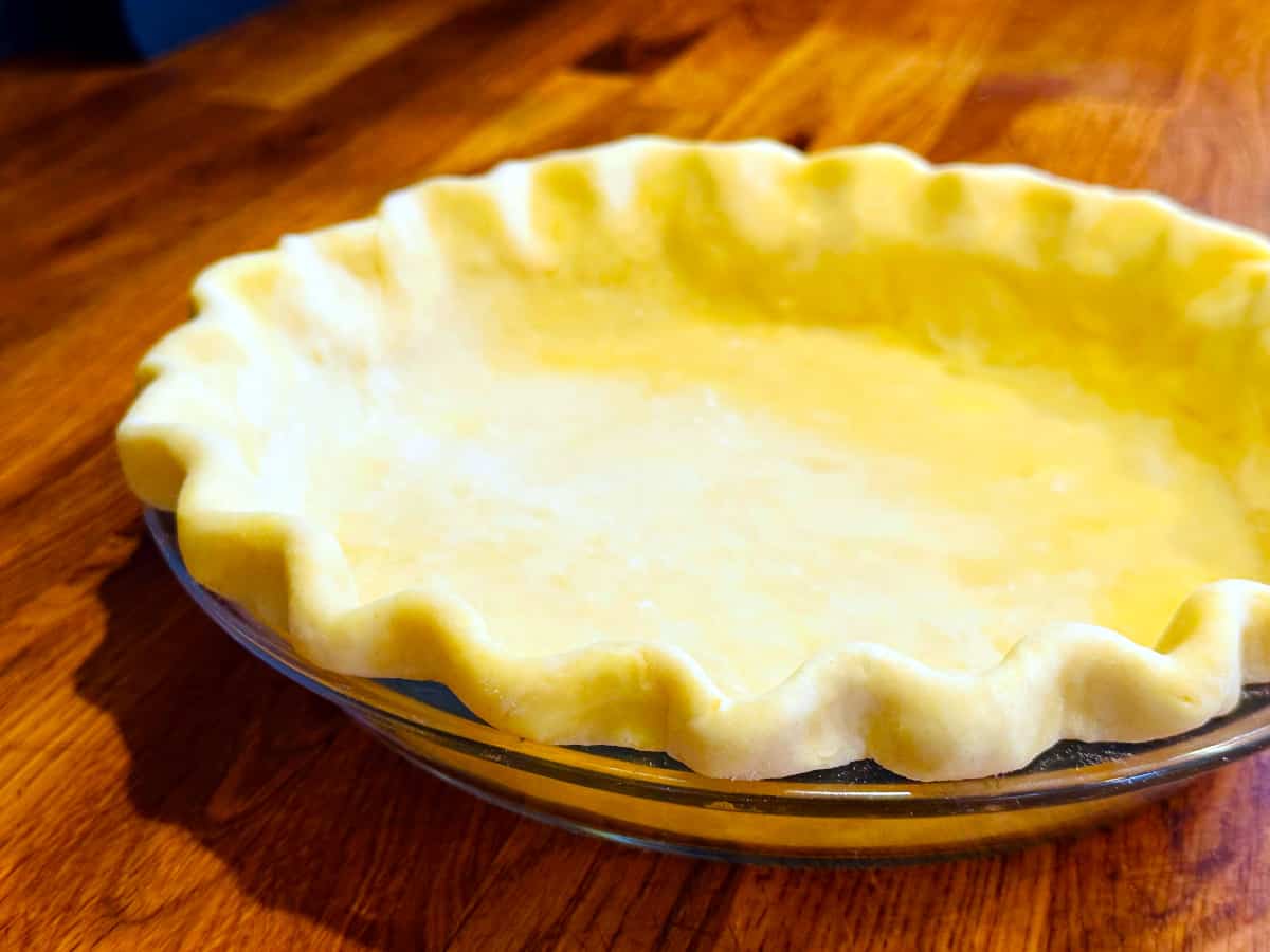 Unbaked pie crust with a crimped edge in a glass pie dish.