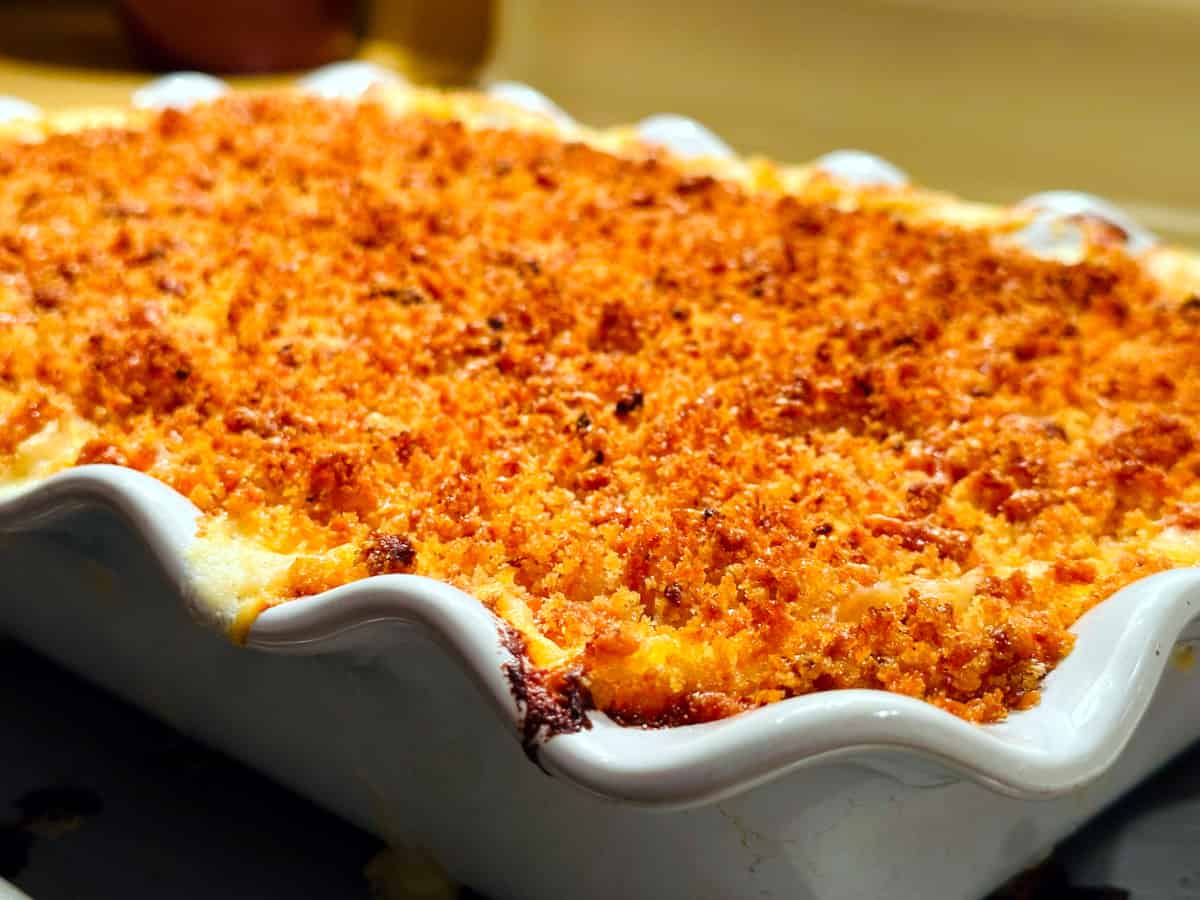 Golden baked macaroni and cheese in a large white baking dish with a ruffled rim.