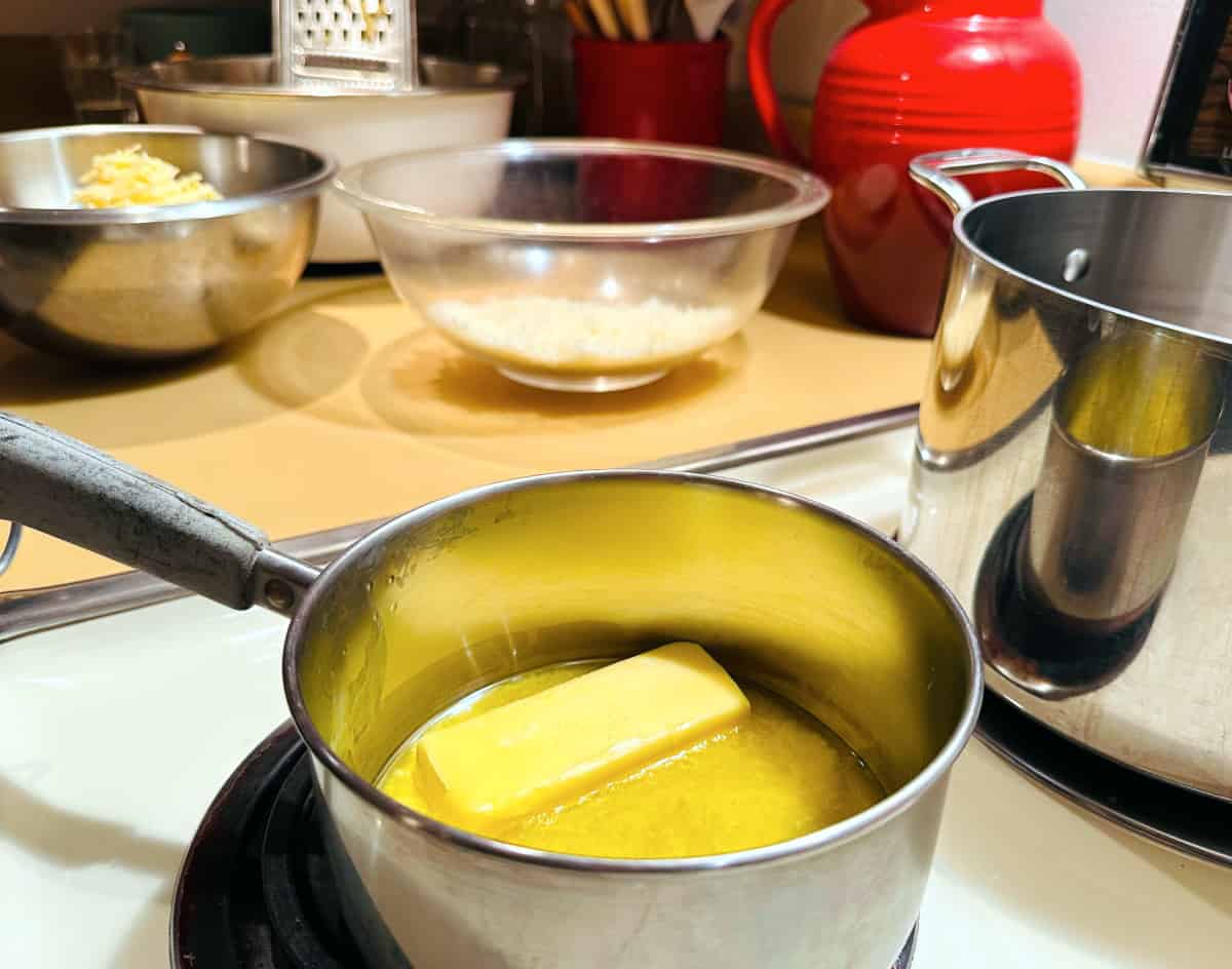 Butter being melted in a small steel saucepan on the stove.