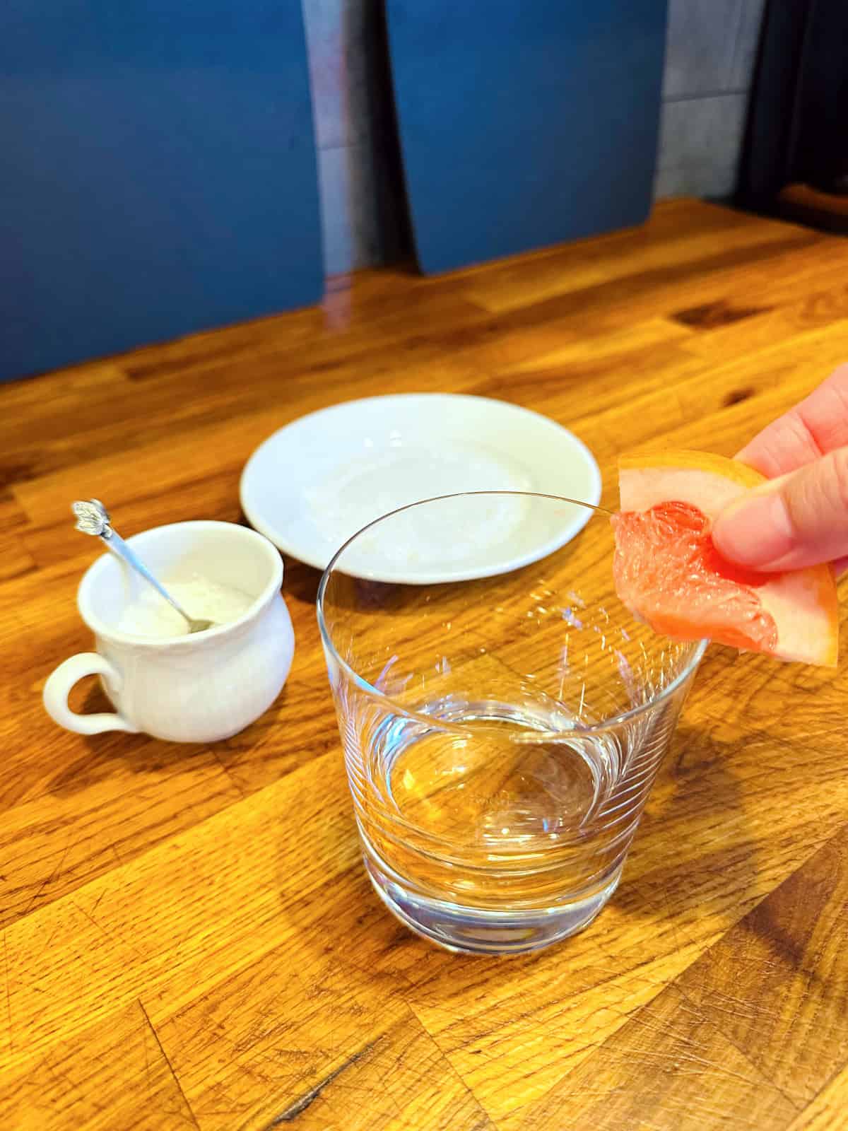 Grapefruit wedge being used to moisten the rim of an old fashioned glass.