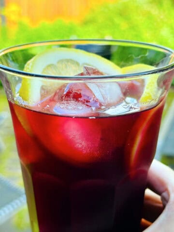 Tall glass of tinto de verano garnished with lemon slices.
