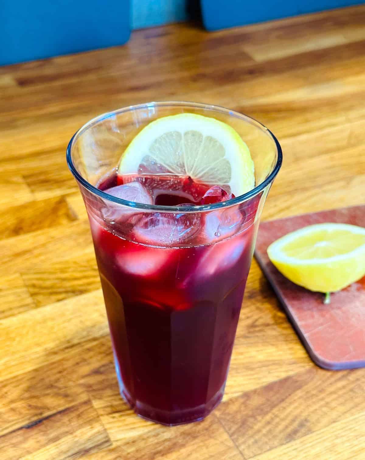Tall glass of tinto de verano garnished with lemon slices.