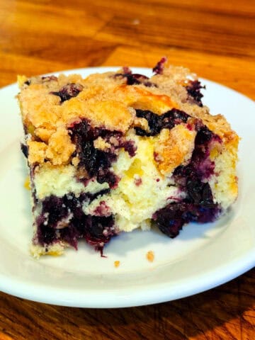 Slice of blueberry buckle served on a small white plate.