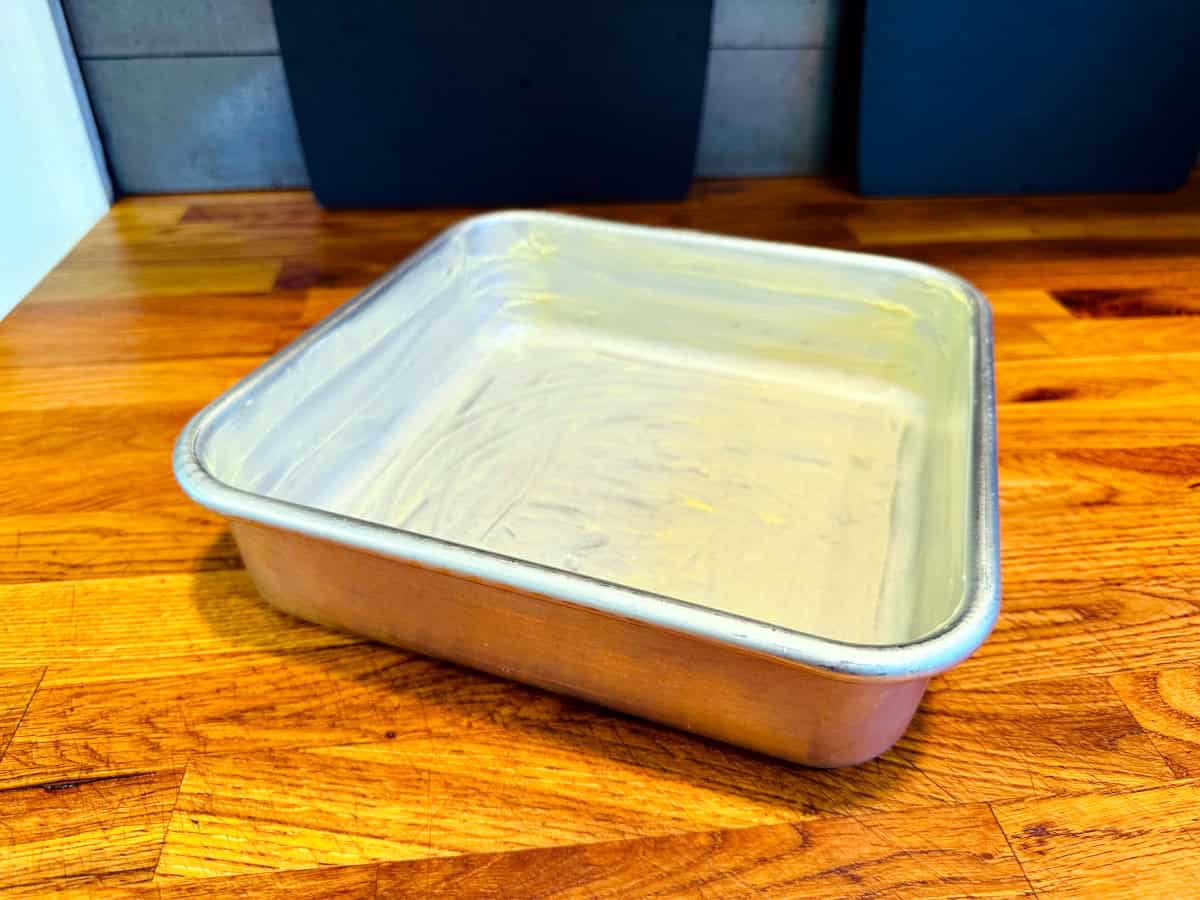 A square metal baking pan greased with butter.