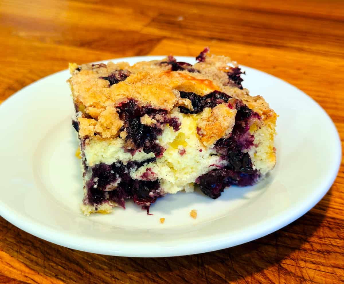 Slice of blueberry buckle served on a small white plate.