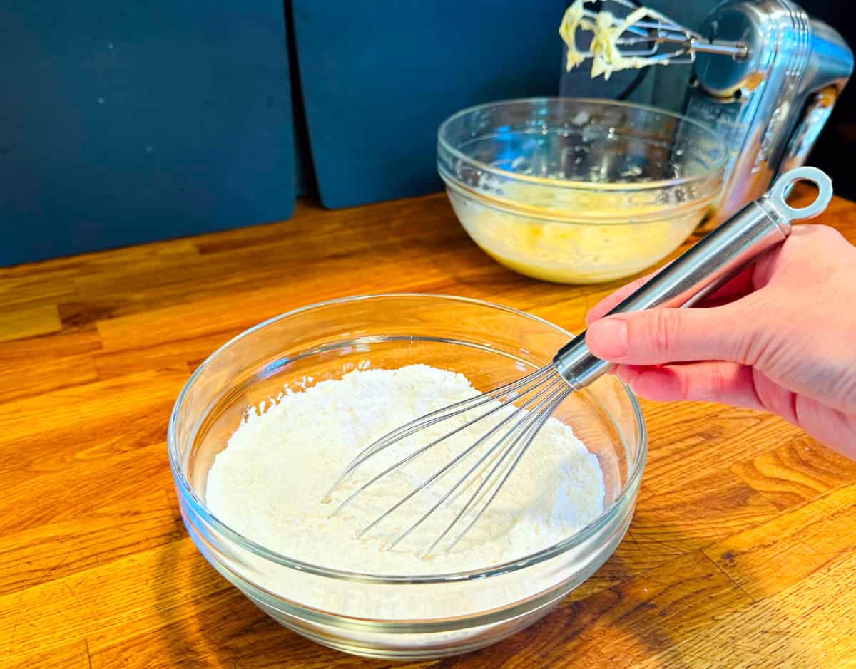 Flour and dry ingredients being whisked in a glass bowl.