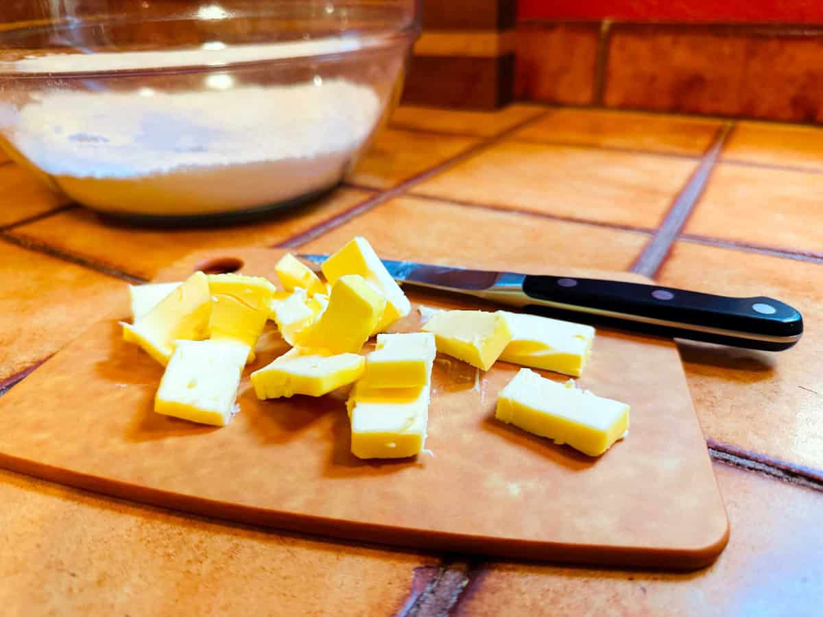 Small pieces of butter on a cutting board with a paring knife.