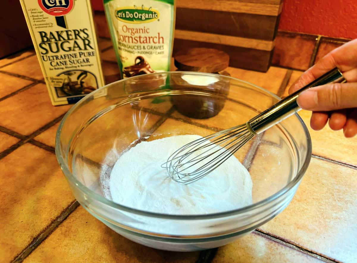 Sugar, cornstarch, and salt being whisked together in a glass bowl.