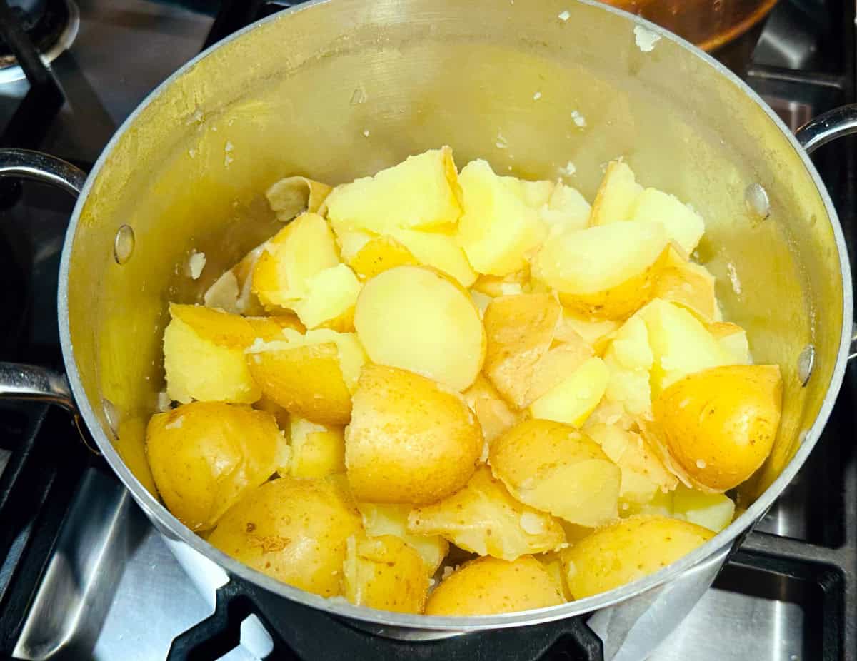 Cooked potato chunks in a steel pot.