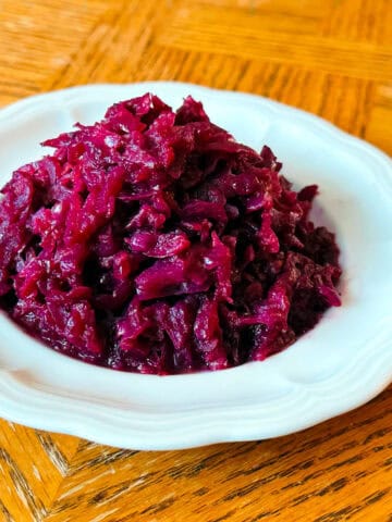 A heap of German red cabbage on a small white scalloped plate.