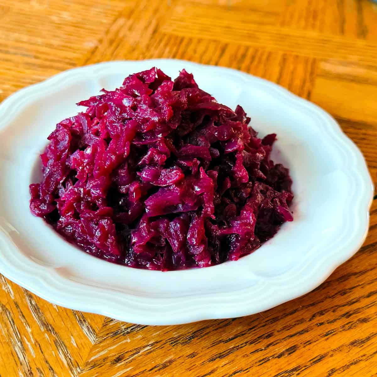 A heap of German red cabbage on a small white scalloped plate.