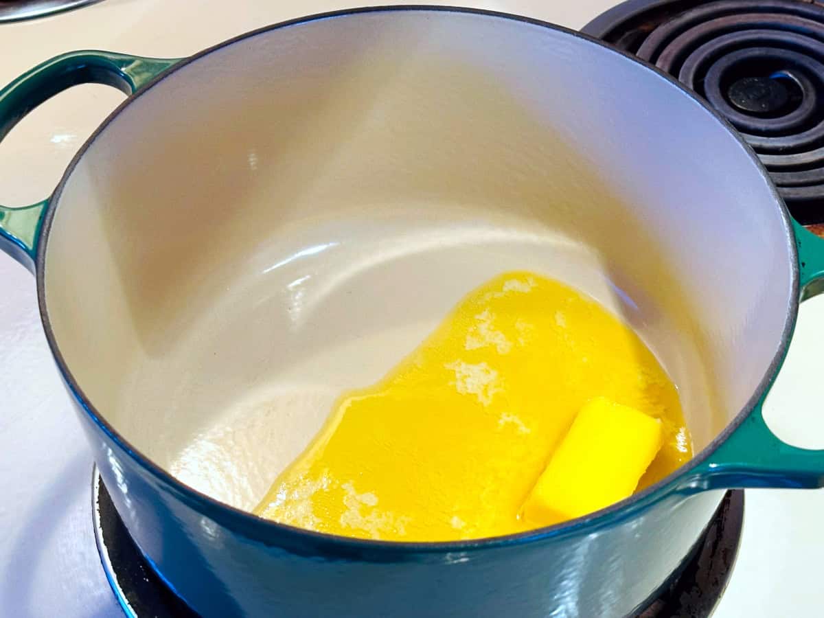 Butter melting in a dark green dutch oven on the stove.