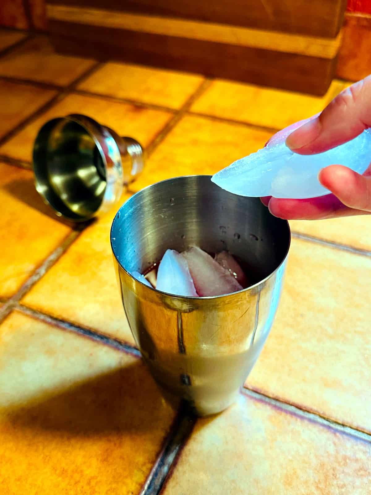 Ice cubes being dropped into a cocktail shaker.