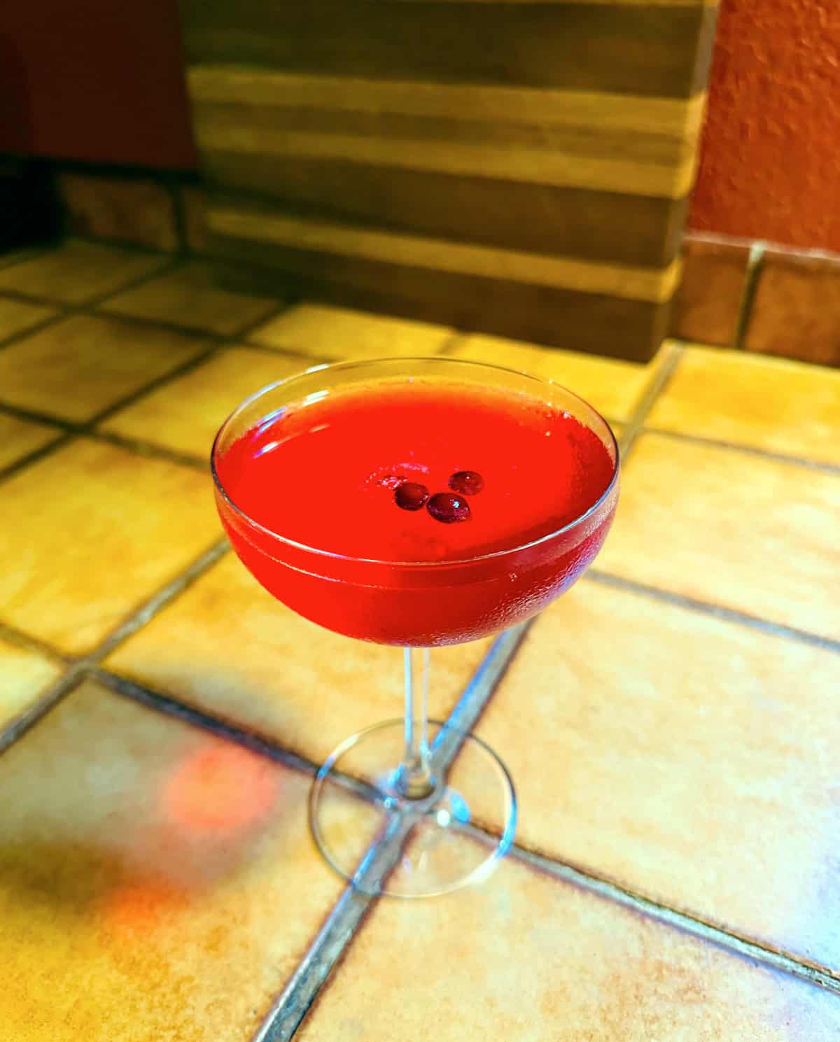 Red Riding Hood (AKA Lingonberry Martini) served in a coupe glass and garnished with three berries.