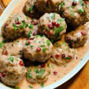 Swedish meatballs sprinkled with chopped parsley in a white serving dish.