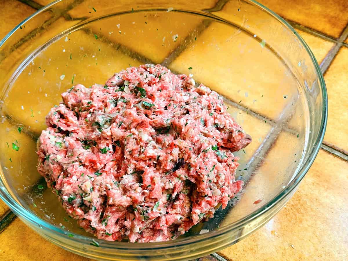 Raw meatball mixture in a glass bowl.