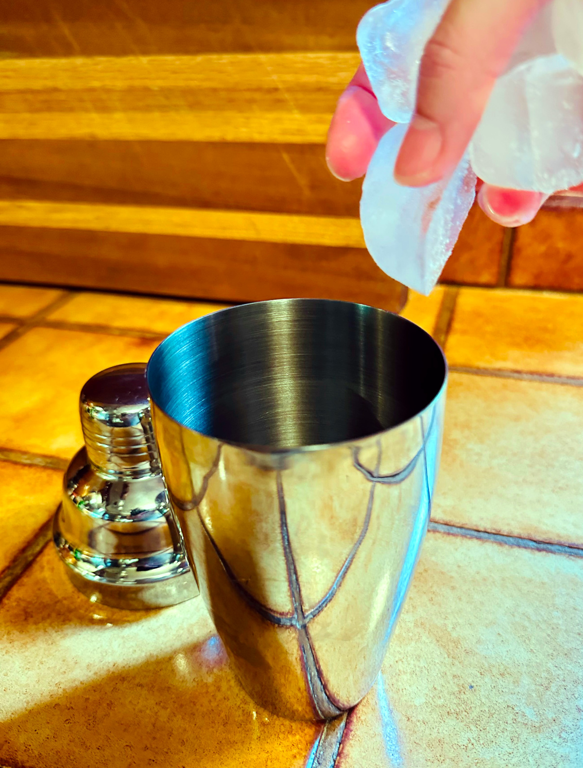 Ice being dropped into a steel cocktail shaker.