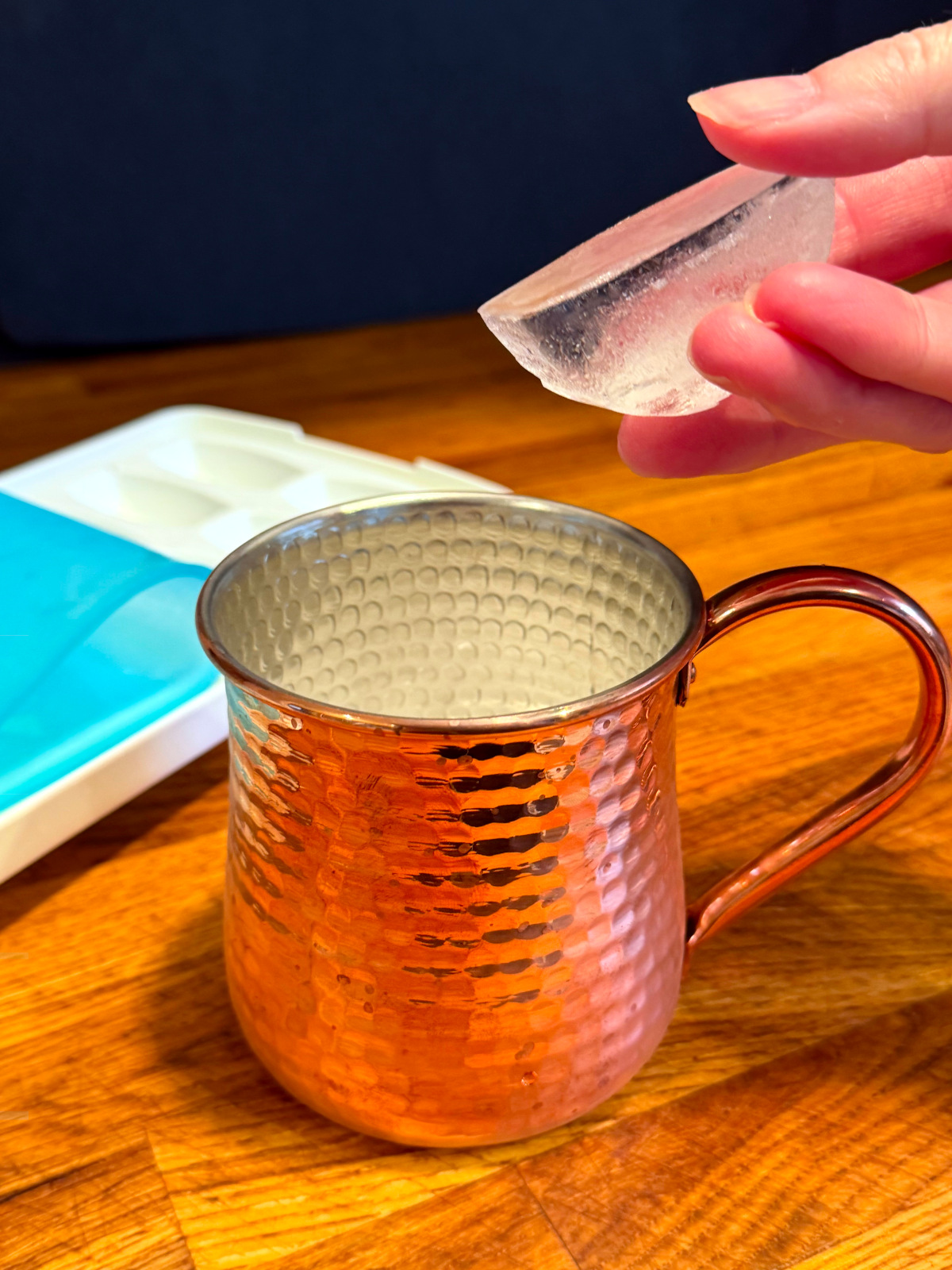 Ice being tossed into a copper mug.