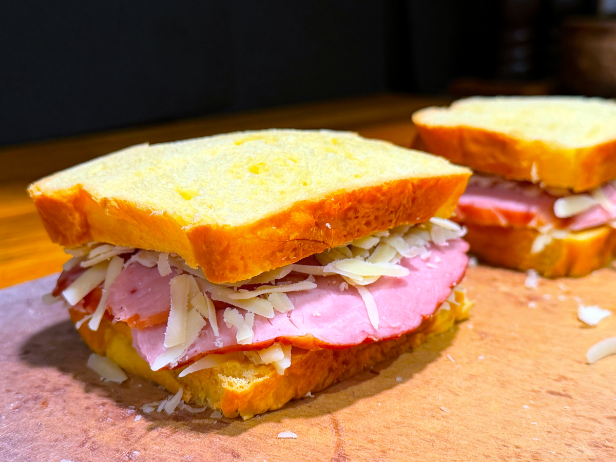 Two assembled sandwiches sitting on a cutting board.