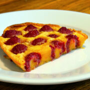 Slice of raspberry flaugnarde sitting on a white plate.