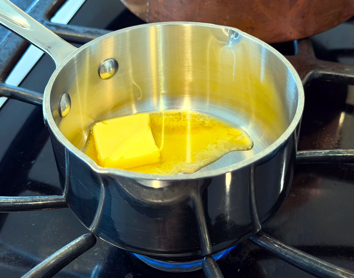 Butter melting in a small steel saucepan on the stove.