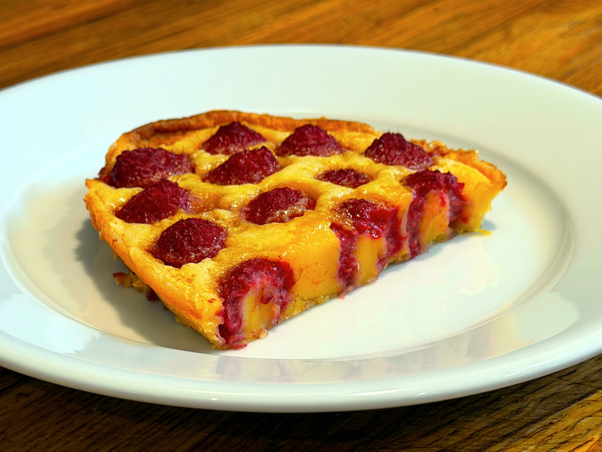 Slice of raspberry flaugnarde sitting on a white plate.
