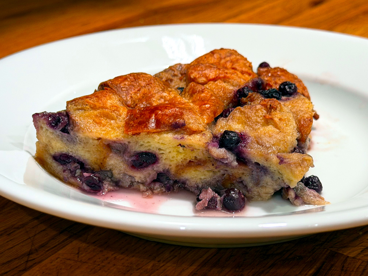 Slice of blueberry bread pudding on a white plate.