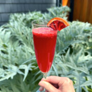 Grande Sicilian Mimosa served in a champagne flute garnished with a thin wedge of blood orange.