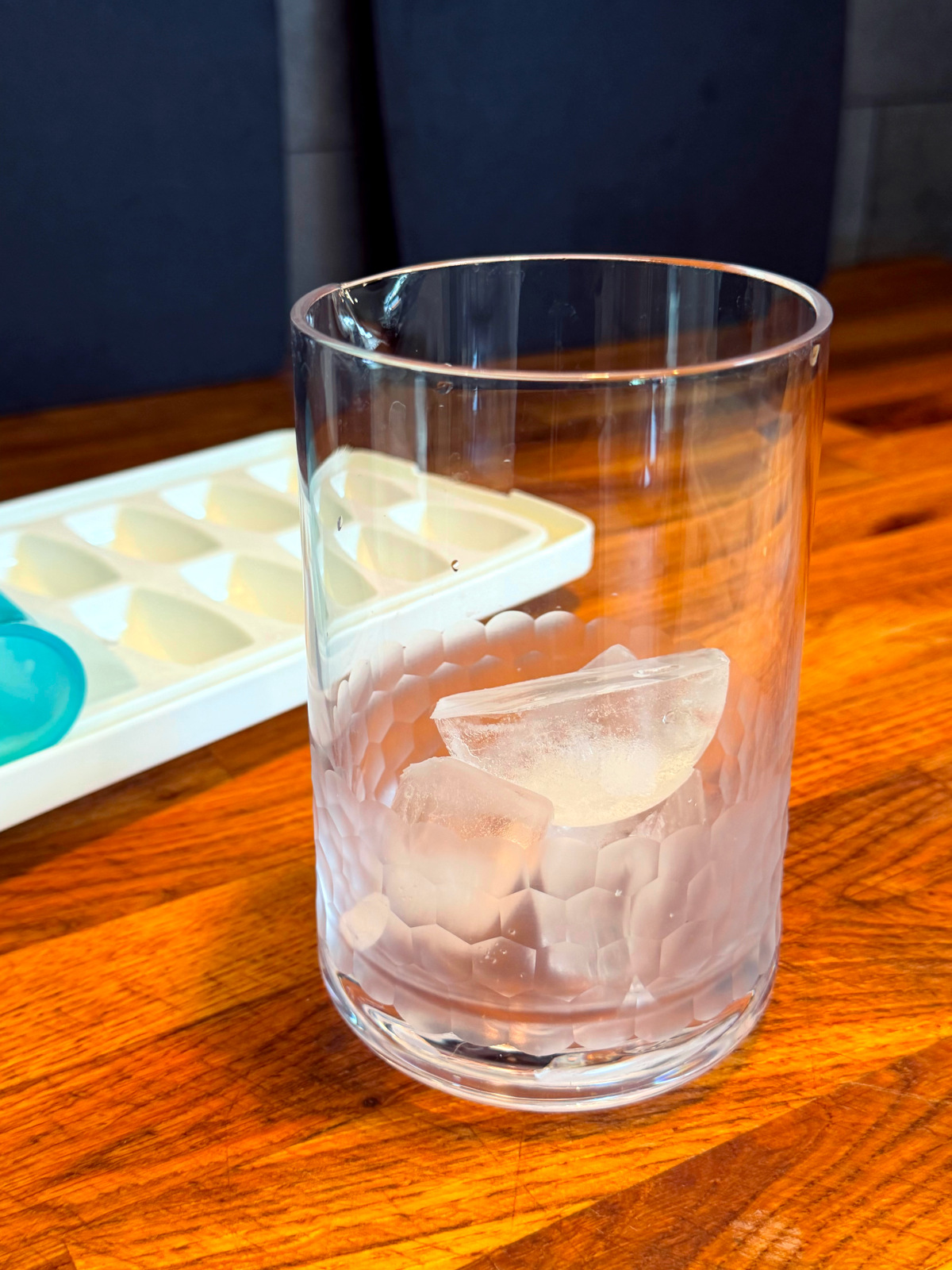 Mixing glass with ice in the bottom next to an ice tray.