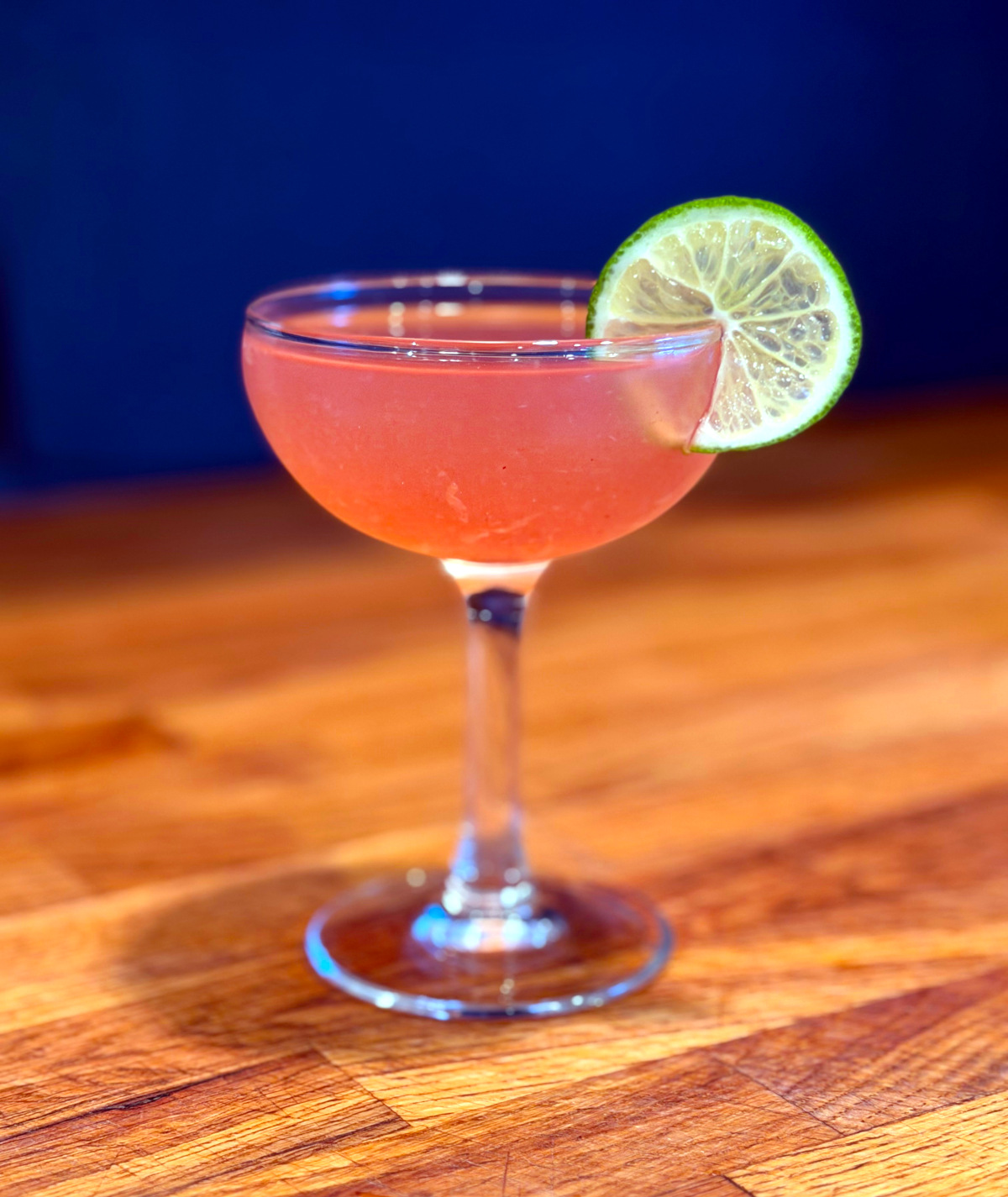 Pink daiquiri served in a coupe glass garnished with a lime wheel.