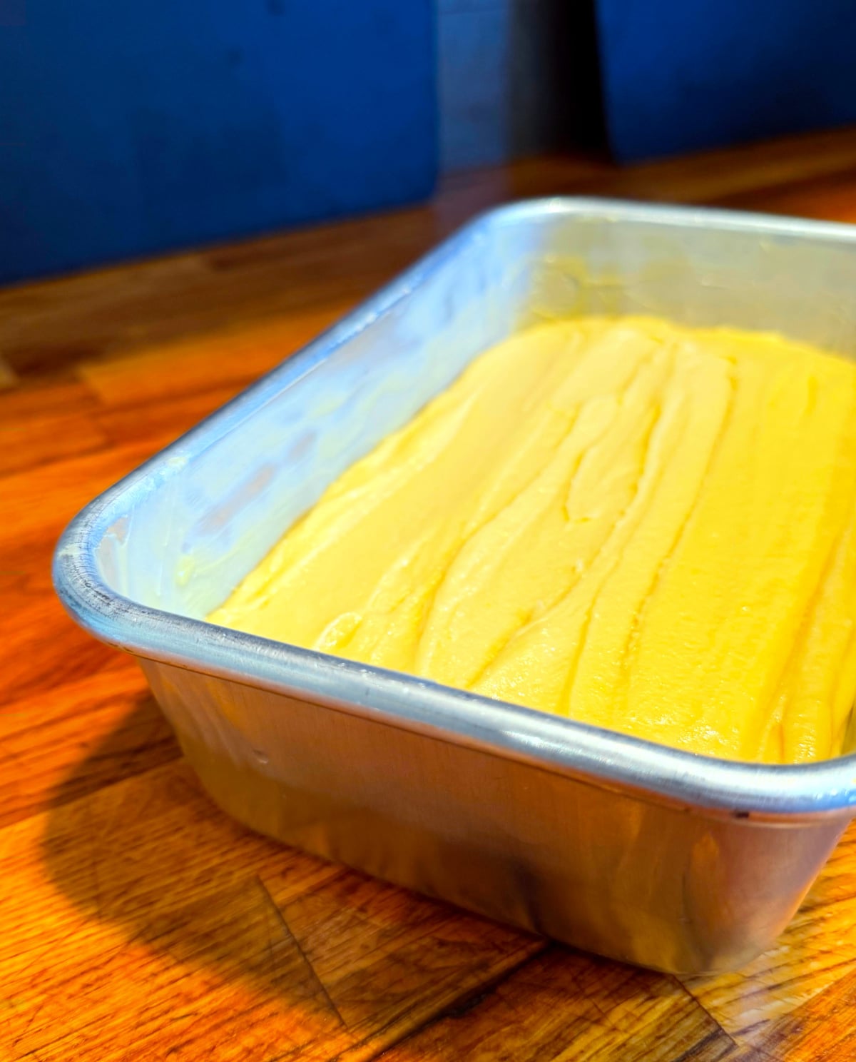 Golden yellow cake batter in a metal loaf pan.